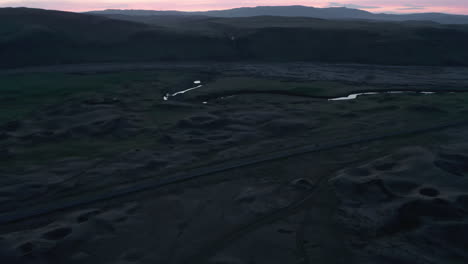 Birds-eye-sunset-over-river-flowing-by-Ring-road,-the-most-important-highway-in-Iceland.-Aerial-view-of-icelandic-most-famous-freeway-that-runs-all-over-the-island-connecting-the-regions