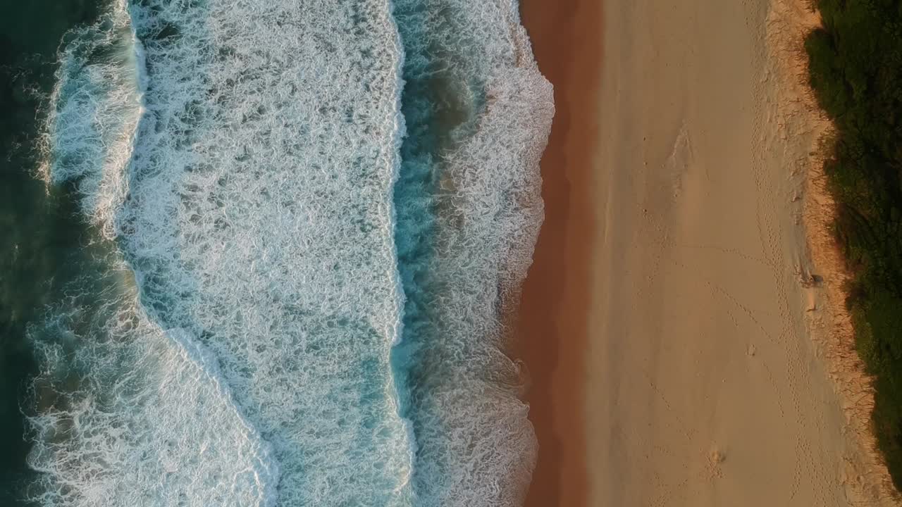 Beautiful blue waves onto orange shoreline, high birds-eye aerial view
