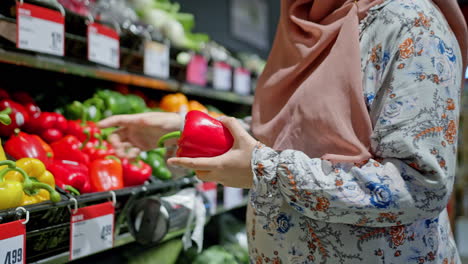 muslim young pregnant woman close up belly shopping searching in vegetables section in fancy grocery store colorful bright in slow motion