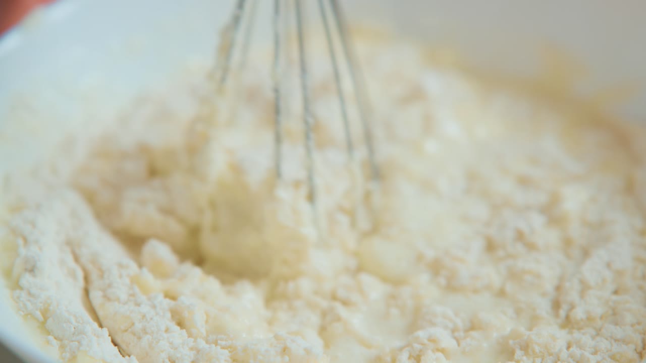 A Step-by-Step Process of Mixing Ingredients: Observing the Transformation of Flour Mixture with a Whisk for Culinary Creations