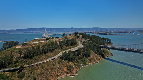 San-Francisco-California-Antena-V103-Tráfico-Pesado-En-El-Puente-De-La-Bahía-Cruzando-El-Estuario,-Vehículos-Que-Pasan-A-Través-Del-Túnel-En-La-Isla-De-Yerba-Buena-Con-Vistas-Al-Paisaje-Urbano-De-Oakland---Filmado-Con-Cine-Mavic-3---Mayo-De-2022