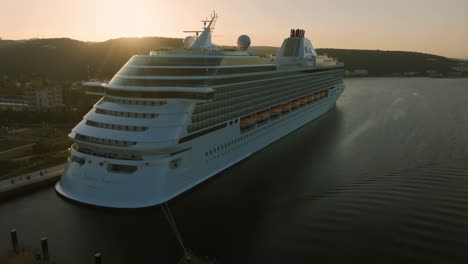 a luxury cruise ship docked in a harbor during sunset
