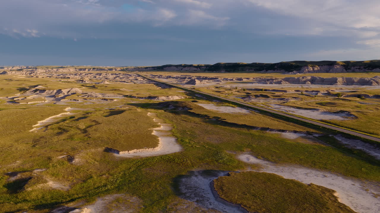 Drone Flight Over Road Leading Through Badlands at Golden Hour Glow