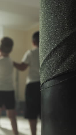 los niños aprenden a pelear con un instructor en el club de boxeo. los niños pequeños hacen golpes fuertes con un entrenador profesional en el gimnasio de boxe o en cámara lenta. desarrollo de los niños