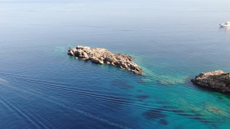 drone view in greece flying over blue sea in loutro with rocks on the water on a sunny day