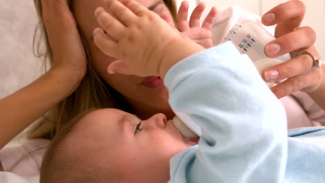 Baby-being-fed-bottle-with-mother-on-bed