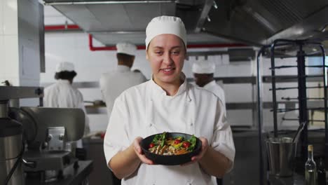 Portrait-of-caucasian-female-chef-presenting-dish-and-looking-at-camera