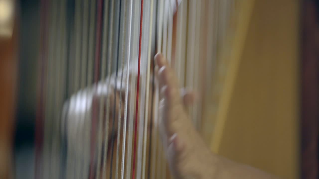 Hænder spiller harpe i slow motion.