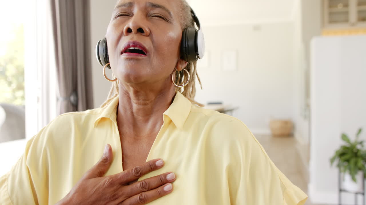 A senior African American woman is enjoying music with headphones