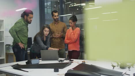 Diverse-group-of-work-colleagues-looking-at-laptop-and-discussing-in-meeting-room