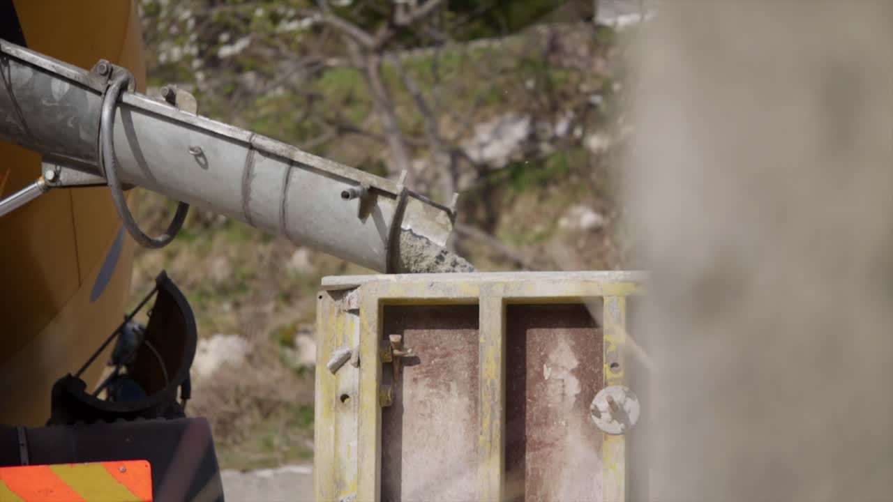 Close-up view when a mixer vehicle pouring the cement into the loading truck.