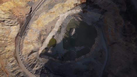 aerial drone view of an active mine with conveyor belts moving crushed rock towards quarry stockpiles under bright sunlight