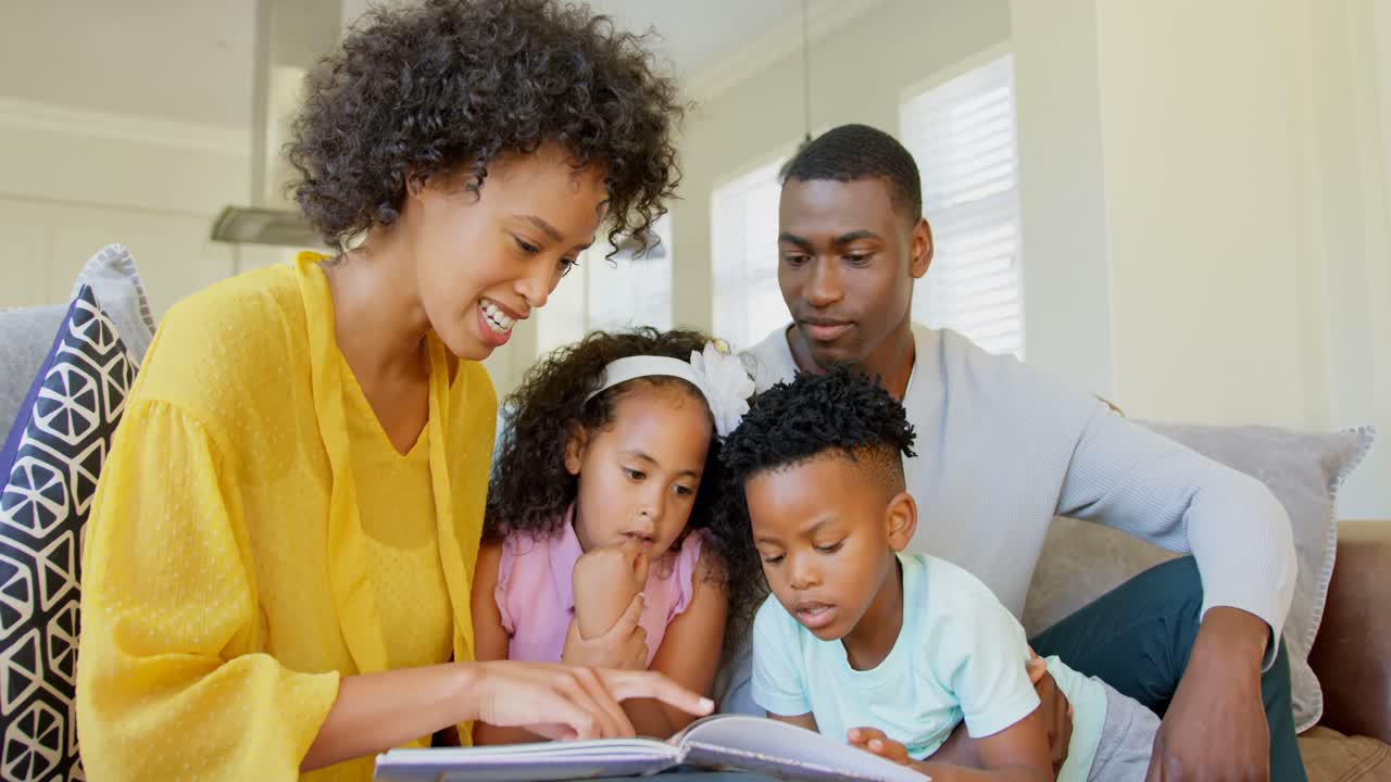 Vorderansicht einer schwarzen Familie, die im Wohnzimmer ein Geschichtenbuch liest, 4K