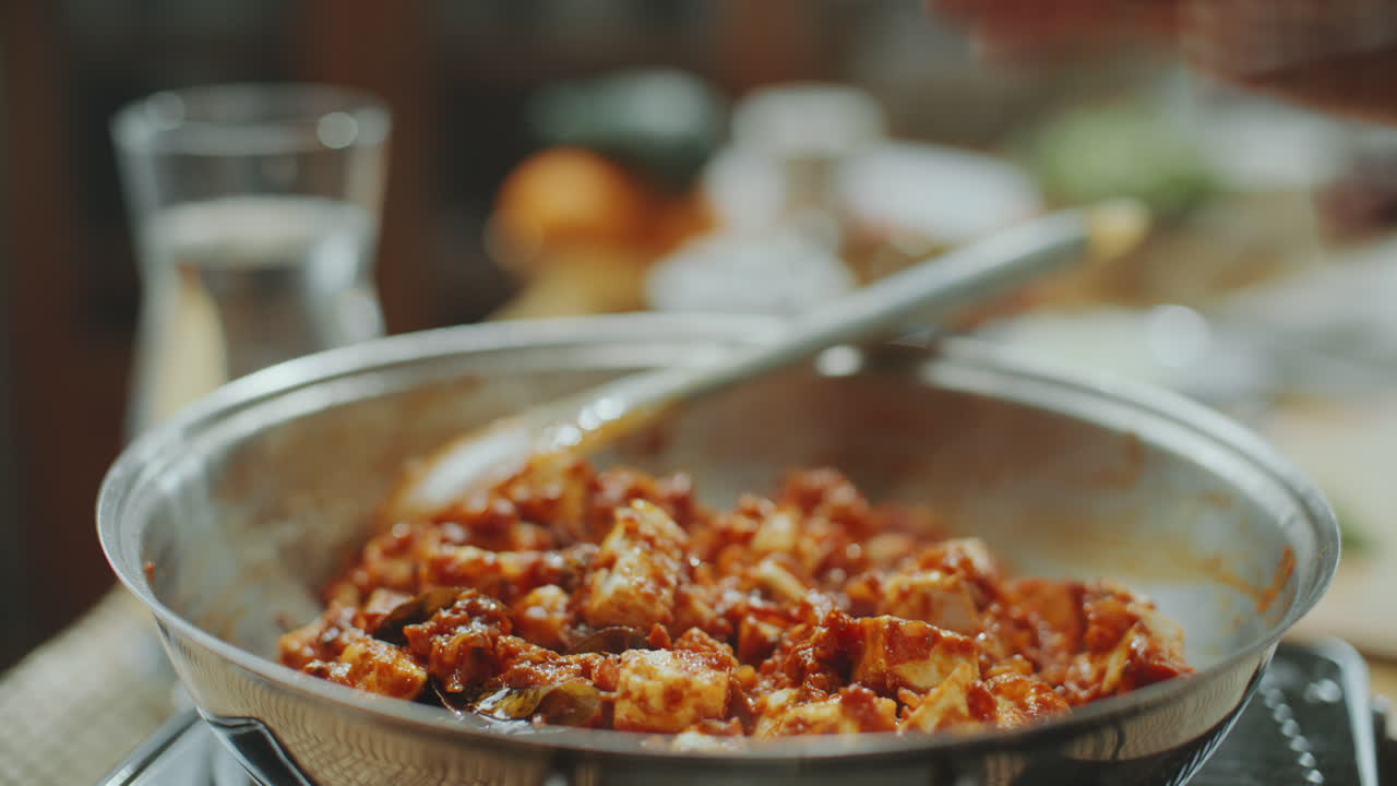 la mano del chef indio agitando paneer en rica salsa de tomate con especias en la sartén
