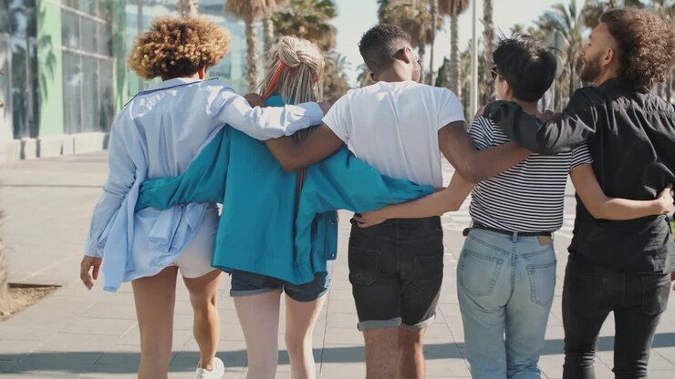 Happy stylish friends waving at camera on street