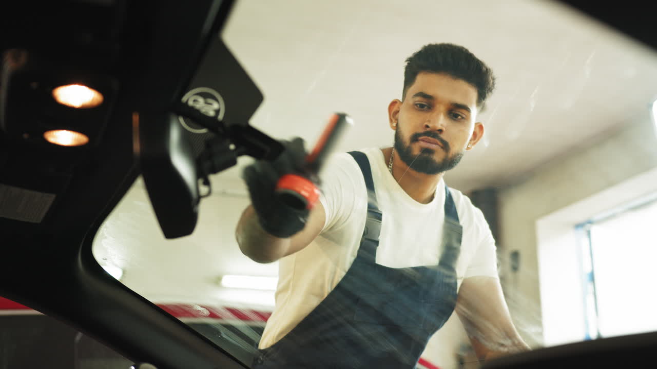 차고 에서 차 앞 유리창 을 청소 하는 사람