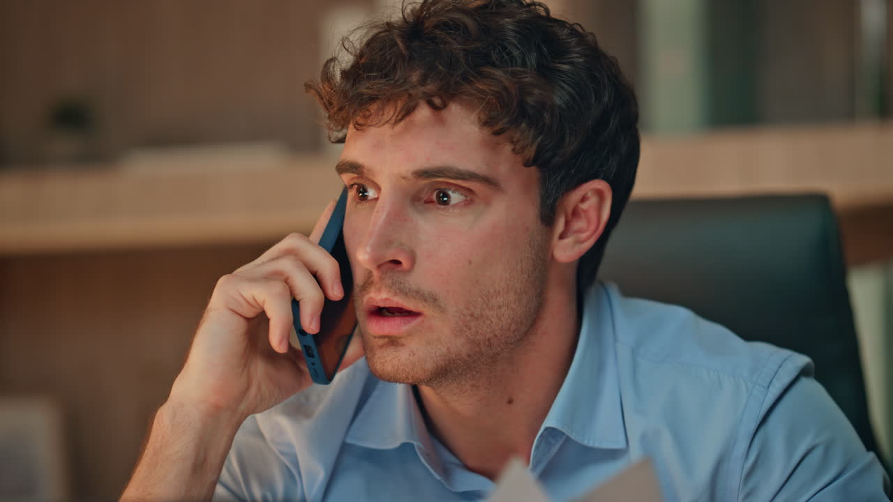 Furious executive shouting mobile phone holding papers in evening room close up.