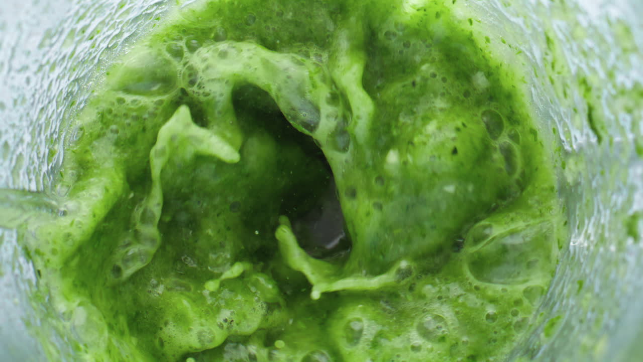 Frullatore elettrico che frulla verdure, frutta ed erbe aromatiche in super slow motion, primo piano