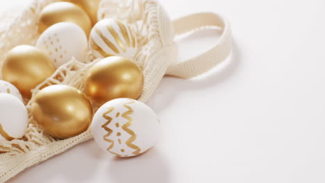 bag with white and gold easter eggs on white background with copy space
