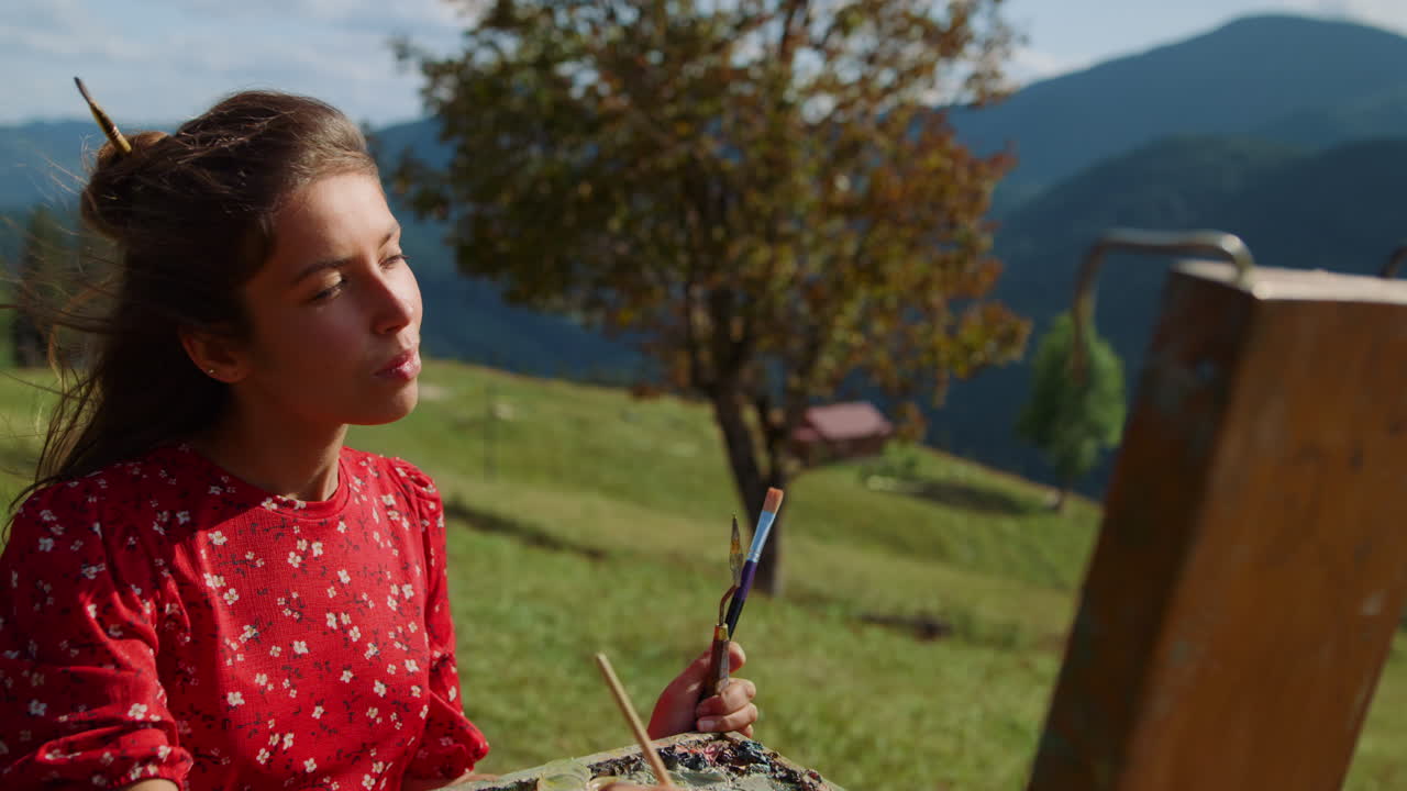Artista donna che mescola i colori sulla tavolozza dipingendo un prato verde, primo piano.
