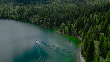 Aerial-video-from-a-drone:-Mountain-lake,-boat-fishing,-pine-forest,-forest-homes-with-docks-in-Canada