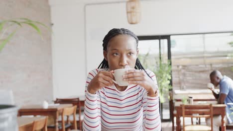 Mujer-Afroamericana-Tomando-Café-En-La-Mesa-De-La-Cafetería,-Cámara-Lenta