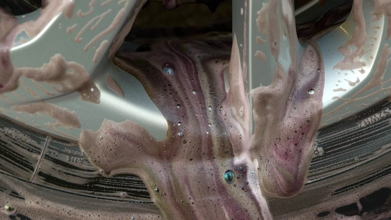 Close up of dirty wheel cleaning product coming off the wheels - brown and purple
