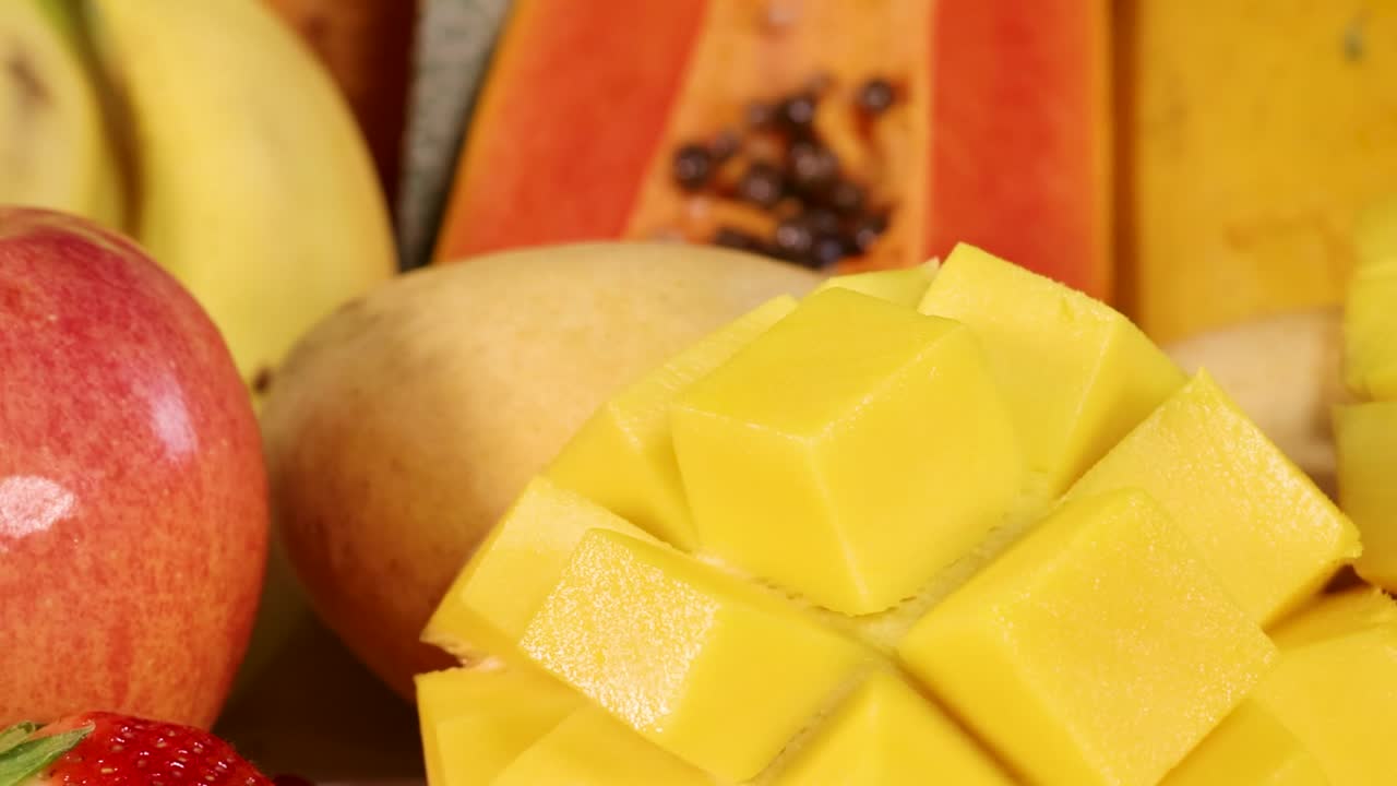 Primo piano vivace di mango, kiwi, fragole e mele rosse affettati, disposti fittamente