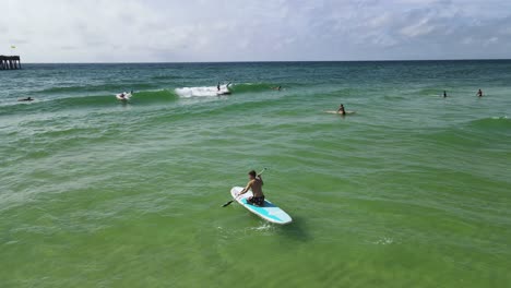 young adult tourist on florida vacation enjoying ocean waves on paddleboard