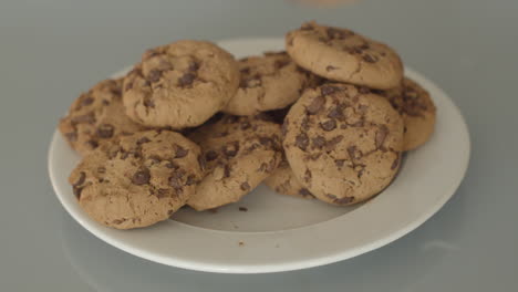 hand placing chocolate chip cookies on pile of cookies - high angle