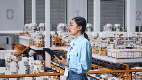 side view of asian business woman using tablet and and looking around in the warehouse