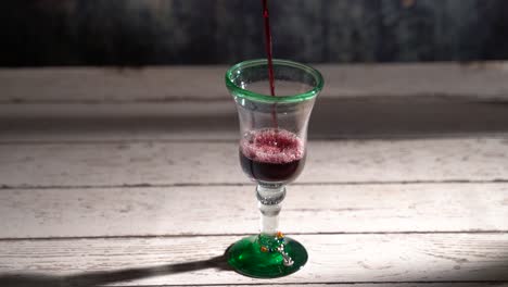 clip de vino tinto en bucle sin costuras que se vierte en un vaso rústico con fondo azul