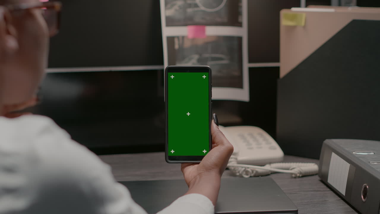 mujer usando un teléfono inteligente con pantalla verde en la oficina