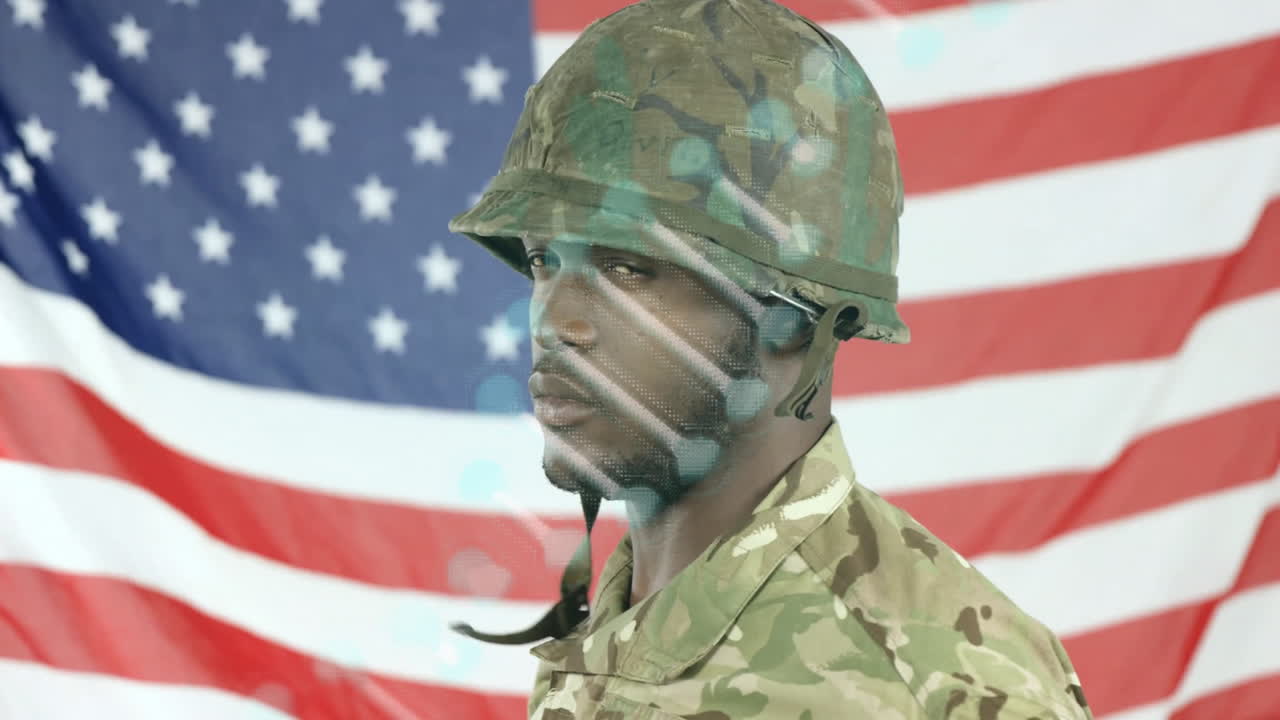 Adjusting helmet with digital interface, soldier standing in front of American flag