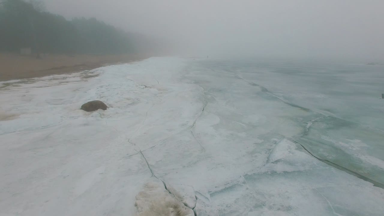 외로운 남자는 얼어붙은 바다 해안의 눈과 얼음을 걸어다닙니다.
