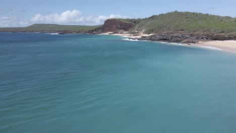 Aerial-Drone-shot-of-turquoise-water-empty-white-sand-beach-on-sunny-day