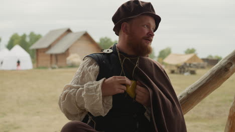 Bearded-man-in-medieval-clothing-talks-standing-in-yard