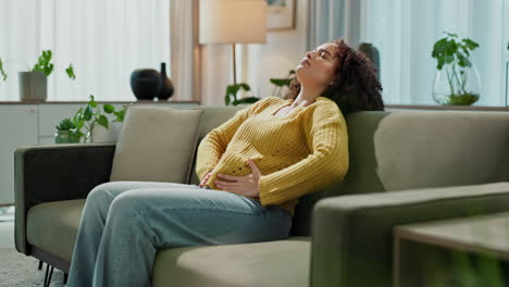 woman experiencing stomach pain on couch