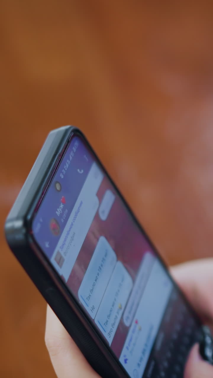 vista parcial de alguien hablando por teléfono en la mesa, participando en una conversación, con un claro enfoque en la mano y el teléfono mientras que un fondo borroso da un entorno personal e íntimo