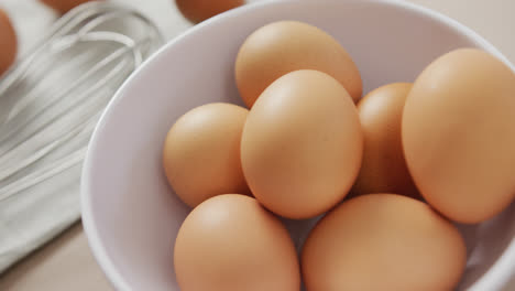 Video-of-close-up-of-eggs-and-egg-whisk-on-rustic-cloth-on-beige-background