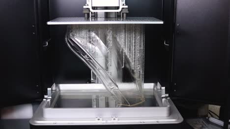 3d printer creating the final layers for a car's full-size headlight lens in clear resin for the automotive industry