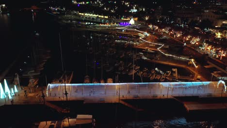 Exposición-De-Arte-De-Luces-Navideñas-Con-Coloridos-Tubos-Iluminados-En-El-Puerto-Deportivo-De-Funchal,-Antena