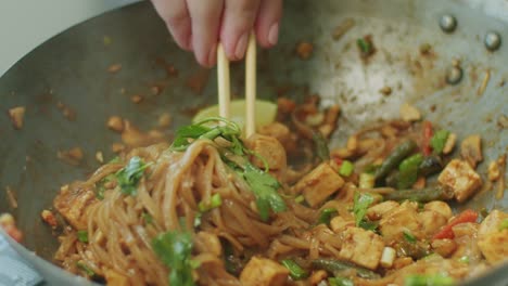 mujer mezclando deliciosos fideos de wok con palillos