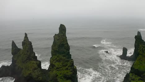 epic moving drone shot of cliffs, dangerous black sand beach in vík. reynisfjara, mount reynisfjall, dyrholaey promontory, iceland