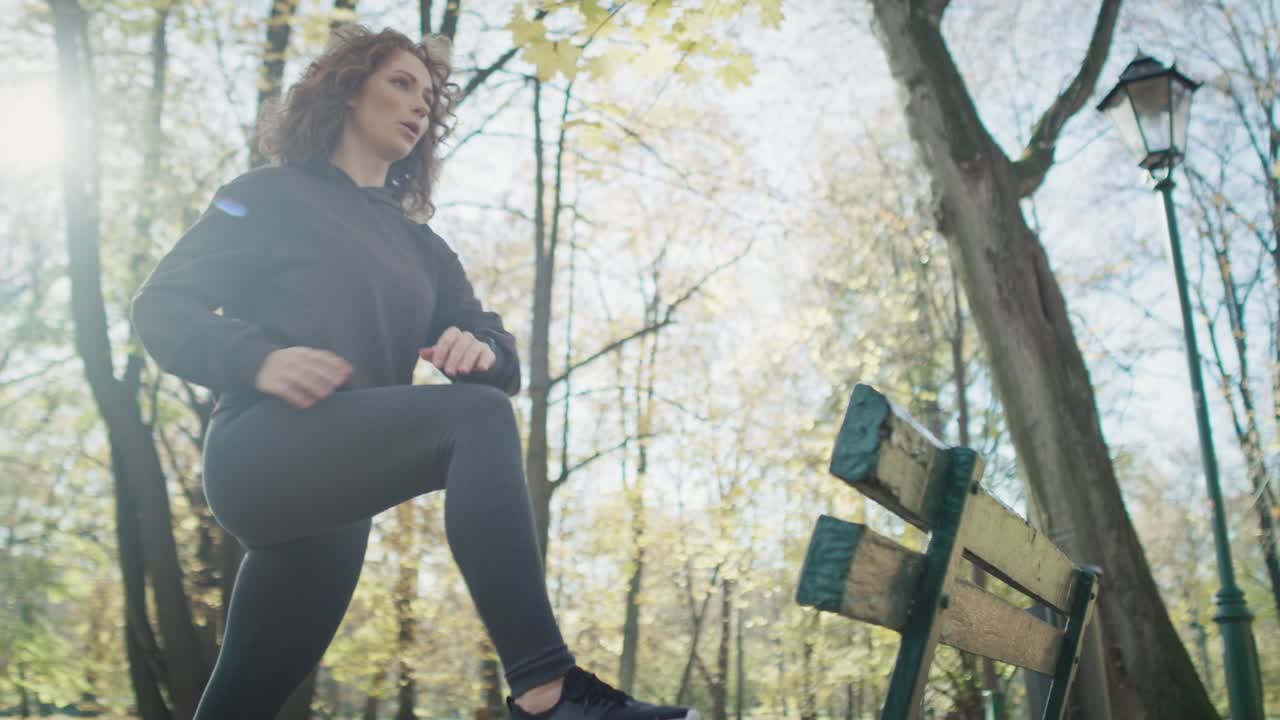 mujer de jengibre calentándose antes de correr en el parque en otoño