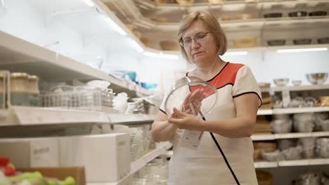 senior woman shopping for glass bowls in a grocery store