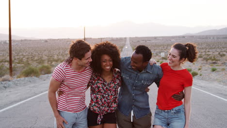 four happy friends standing on a desert highway, close up