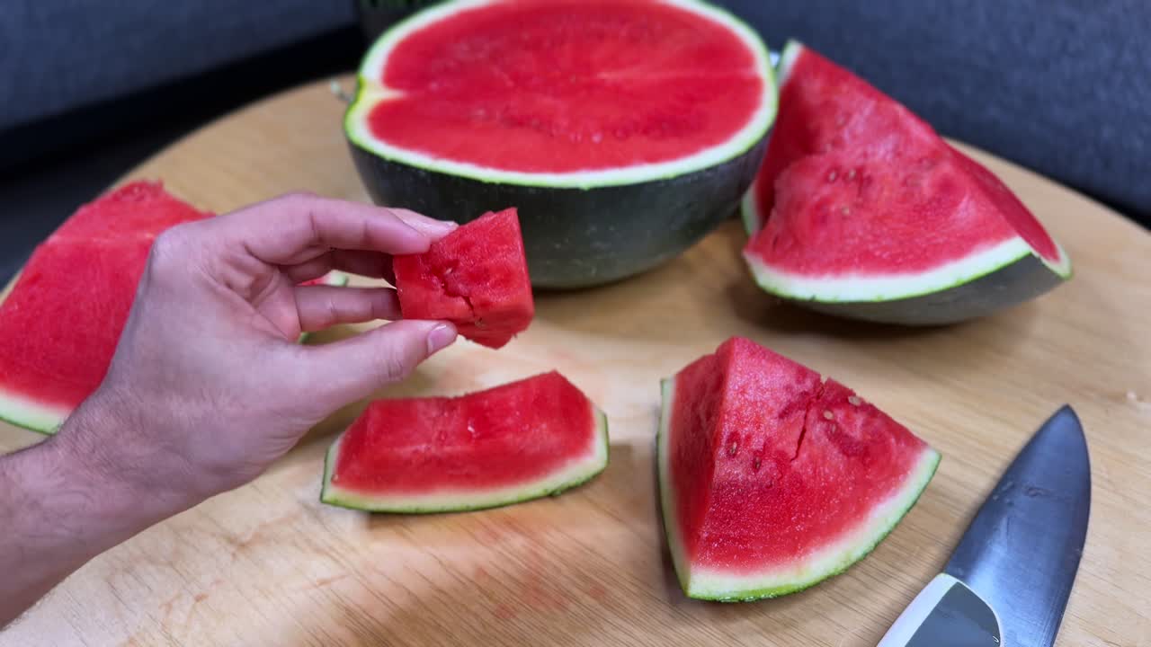 Close-up of hands breaking a fresh watermelon slice with seeds on a cutting board, ideal for food, lifestyle, health, nutrition, and advertising projects