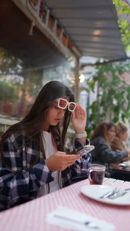 woman checking smartphone in outdoor cafe