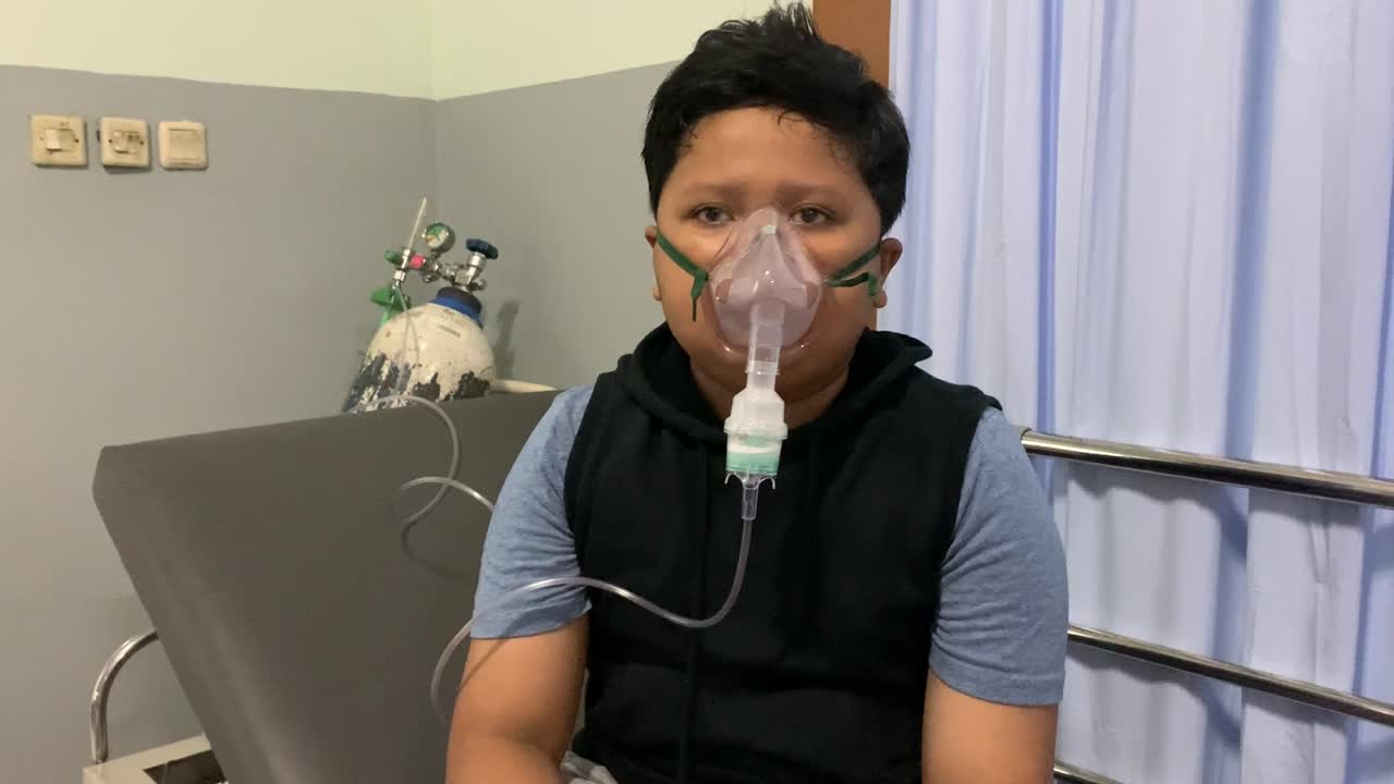 niño asiático hace inhalación con nebulizador de oxígeno en el hospital